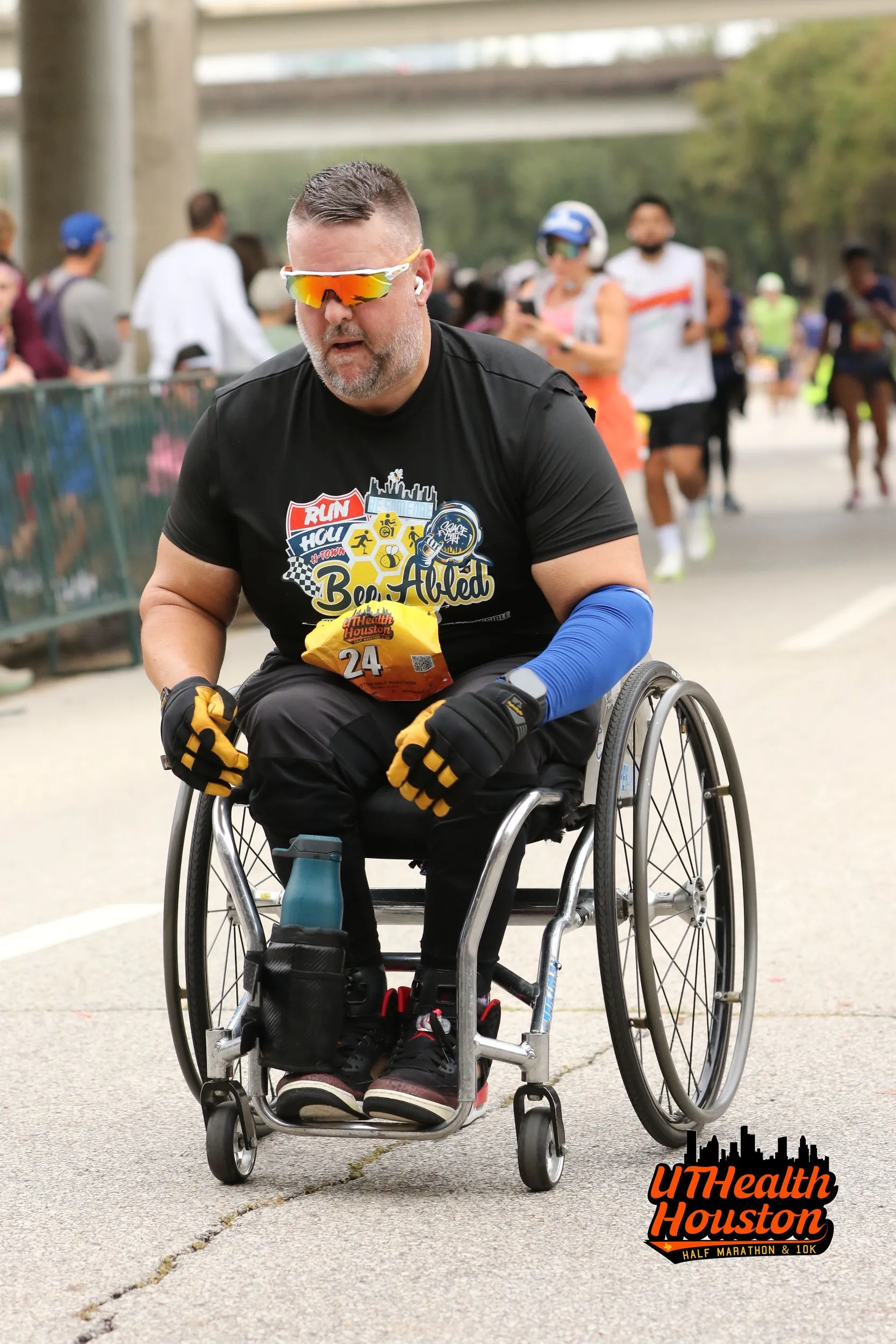 Douglas Dillard racing in his wheelchair at the UTHealth Houston Half Marathon, wearing a Bee Abled jersey